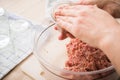 Woman filling raw mixed minced meat with pork and beef in screw-cap and preserving mason glass jars on towel for home-made