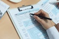 Woman filling in U.S. Individual income tax return, tax 1040 at table.