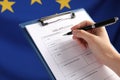 Woman filling visa application form against flag of European Union, closeup Royalty Free Stock Photo