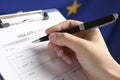 Woman filling visa application form against flag of European Union, closeup Royalty Free Stock Photo