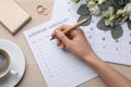 Woman filling Wedding Checklist at wooden table, top view Royalty Free Stock Photo