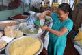 A woman fills a bag with sugar at her stall in the Ba Le market in Hoi An