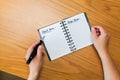 Woman fills in her goals and plans for long and short terms in spiral notepad on wooden table, top view Royalty Free Stock Photo