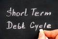 Woman fingers with chalk writing words Short Term Debt Cycle on black board