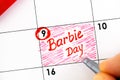 Woman fingers with pen writing reminder Barbie Day in calendar