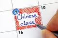 Woman fingers with pen writing reminder Chinese Class in calendar