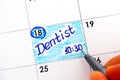 Woman fingers with pen writing reminder Dentist 10-30 in calendar