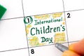 Woman fingers with pen writing reminder International Children`s Day in calendar