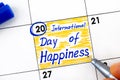 Woman fingers with pen writing reminder International Day of Happiness in calendar