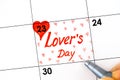 Woman fingers with pen writing reminder Lover`s Day in calendar