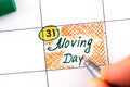 Woman fingers with pen writing reminder Moving Day in calendar