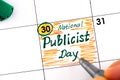 Woman fingers with pen writing reminder National Publicist Day in calendar