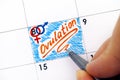 Woman fingers with pen writing reminder Ovulation in calendar.