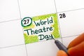 Woman fingers with pen writing reminder World Theatre Day in calendar