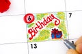 Woman fingers with pen writing reminder Birthday in calendar