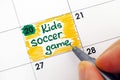 Woman fingers writing reminder Kids Soccer Game in calendar