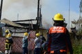 Woman Fire Fighter With Protective Hat supervising fire volunteers in extinguishing house fire Royalty Free Stock Photo