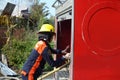 Woman Fire Fighter With Protective Hat working on fire truck pump hose