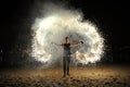 Woman fire juggler performing at night on the sandy beach.