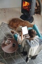 woman by the fireplace, sitting in a cozy armchair, with a warm