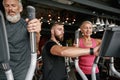 Woman first time at gym, trainer helping to set up equipment