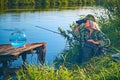 Woman fisherman carefully looks through binoculars on the river bank. Summer, hobby, vacation.