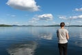 Woman fisherman catches fish on the background of a beautiful blue lake and sky with clouds. Bright shot