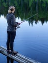 Woman fishing on a fishing rod from a wooden pier Royalty Free Stock Photo