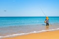 Woman fishing standing in the water near the shore. The sky is dropping the plane. Sunny clear morning on a tropical beach