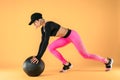 Woman in fitness clothes training with a medicine ball. Female athlete doing abdomen workout using a medicine ball