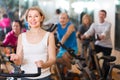 Woman on fitness cycle with people