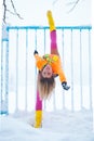 Woman fitness instructor workout outdoor in snow by the metal fence winter