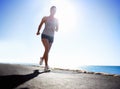 Woman, fitness and running on beach for workout, exercise or outdoor training on a sunny day. Female person, athlete or Royalty Free Stock Photo