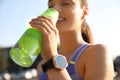 Woman with fitness tracker drinking water after training outdoors, closeup Royalty Free Stock Photo