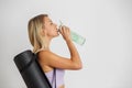 Woman fitness trainer holding yoga mat and drinking water from refillable bottle. Motivation concept Royalty Free Stock Photo