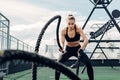 Woman in fitness wear working out with two battle ropes Royalty Free Stock Photo