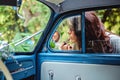 Woman fixing lipstick on a classic car mirror