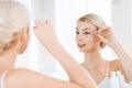 Woman fixing makeup with cotton swab at bathroom