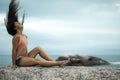 Woman flicking her hair on a rock at sunset on Bakovern Beach, Cape Town.