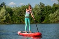 Woman is floating on a SUP board on sunny morning. Stand up paddle boarding - awesome active recreation during vacation.