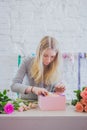 Woman floral artist, florist making gift box with flowers on table