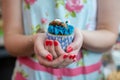 Woman in Floral dress holding cookie monster cupcake