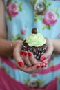 Woman in Floral dress with painted nails holding chocolate cupcake