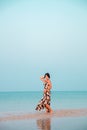 Woman in a floral dress sitting in shallow ocean water. Girl in the sea.