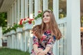 Woman in floral dress smiling near white fence with red flowers Royalty Free Stock Photo