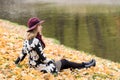 Woman in a floral patterned coat and wine red hat in the park, by the river. Happy girl, colorful autumn forest. Portrait of lady Royalty Free Stock Photo