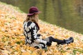 Woman in a floral patterned coat and wine red hat in the park, by the river. Happy girl, colorful autumn forest. Portrait of lady Royalty Free Stock Photo