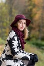 Woman in a floral patterned coat and wine red hat in the park, by the river. Happy girl, colorful autumn forest. Portrait of lady Royalty Free Stock Photo