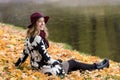 Woman in a floral patterned coat and wine red hat in the park, by the river. Happy girl, colorful autumn forest. Portrait of lady Royalty Free Stock Photo