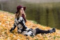 Woman in a floral patterned coat and wine red hat in the park, by the river. Happy girl, colorful autumn forest. Portrait of lady Royalty Free Stock Photo